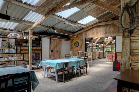 Area comune interna a Glamping de Bosweide con tavoli rustici in legno e luce naturale a Noord-Brabant.