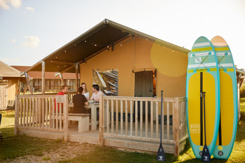Tenda glamping a Erfgoedpark de Hoop, Noord-Holland, quattro persone fuori, due paddleboard accanto.