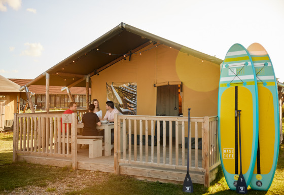 Tienda glamping en Erfgoedpark de Hoop, Noord-Holland, cuatro personas fuera, dos paddleboards al lado.