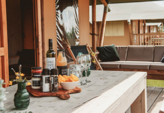 Udendørs glampingbord med snacks, vin og glas foran et luksustelt på Erfgoedpark de Hoop i Nordholland.