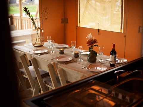 Mesa elegante en tienda glamping en Erfgoedpark de Hoop - Glampingtenten Noord-Holland con vino y flores.