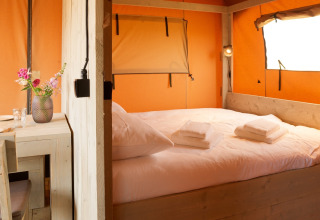 Intérieur d’une tente glamping avec lit double et coin repas à Erfgoedpark de Hoop, Noord-Holland.
