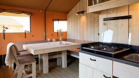 Intérieur d’un hébergement glamping à Erfgoedpark de Hoop, Noord-Holland, avec cuisine, table et coin salon.