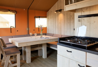 Interieur van een glampingtent in Erfgoedpark de Hoop, Noord-Holland, met keuken, eettafel en zithoek.