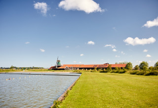 Afbeelding van Erfgoedpark de Hoop Glampingtenten in Noord-Holland met molen, meer en groen grasveld.