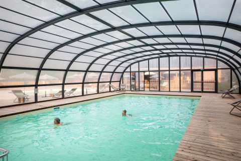 Indoor pool with a transparent arched roof at Village Huttopia Forêt des Vosges glamping accommodation.