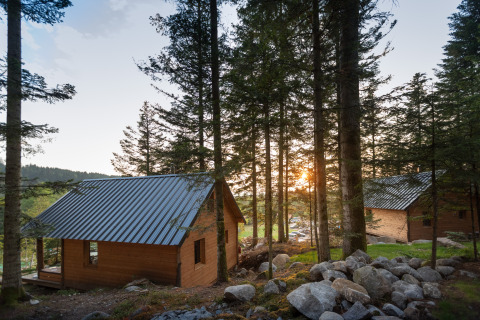 Holzhütten im Wald beim Sonnenuntergang im Village Huttopia Forêt des Vosges - Glamping Vogezen.