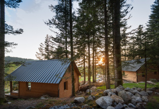 Cabañas de madera entre árboles al atardecer en Village Huttopia Forêt des Vosges - Glamping Vogezen.