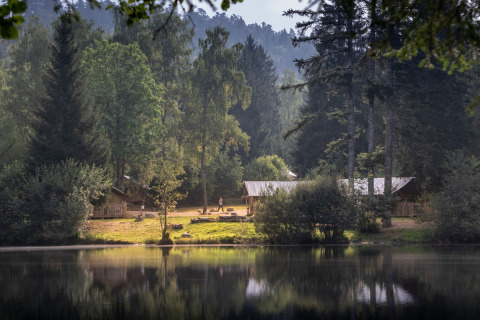 Glamping accommodatie met houten lodges bij een bosmeer bij Village Huttopia Forêt des Vosges, in de natuur.