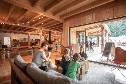 Family enjoys time together inside a cozy wooden cabin at Village Huttopia Forêt des Vosges glamping site.