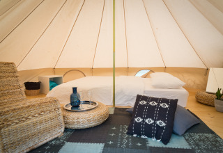 Interior de tienda glamping Sahara en Camping Bellinzona, Suiza, con cama confortable y zona de descanso.