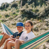Two smiling children relax in a hammock at Surfana Family Camp Bloemendaal, Glamping Noord-Holland.