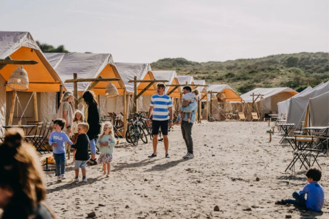 Gezinnen genieten van glamping bij Surfana Family Camp Bloemendaal, omringd door tenten in Noord-Holland.