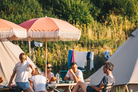 Familier nyder sommerdagen under parasoller ved Surfana Family Camp Bloemendaal, Glamping Noord-Holland.