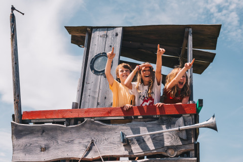 Drie kinderen spelen in een hut bij Surfana Family Camp Bloemendaal, Glamping Noord-Holland op een zonnige dag.