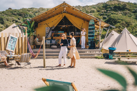 Alloggio glamping al Surfana Family Camp Bloemendaal, tende e persone su una spiaggia sabbiosa in Olanda.