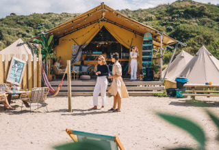 Alloggio glamping al Surfana Family Camp Bloemendaal, tende e persone su una spiaggia sabbiosa in Olanda.