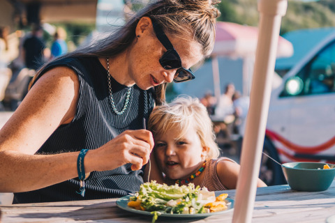Mor og barn spiser sund frokost på Surfana Family Camp Bloemendaal - Glamping Noord-Holland udendørs.