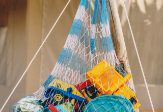 Toys and beach items in a mesh bag at Surfana Family Camp Bloemendaal, Glamping Noord-Holland, Netherlands.
