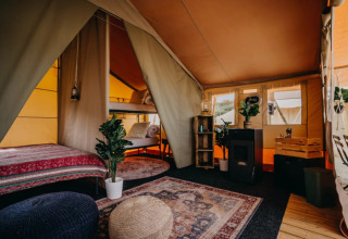 Interior of a glamping tent at Surfana Family Camp Bloemendaal with cozy decor, beds, and boho furnishings.