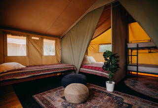 Interno della tenda glamping Surfana Family Camp Bloemendaal con letti, tappeti e luce naturale.