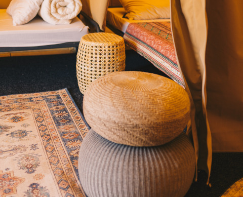 Vista interior de Surfana Family Camp Bloemendaal glamping en Noord-Holland, con pufs y alfombra decorativa.