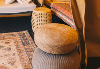 Binnenaanzicht van Surfana Family Camp Bloemendaal glamping Noord-Holland met poefs en decoratief vloerkleed.