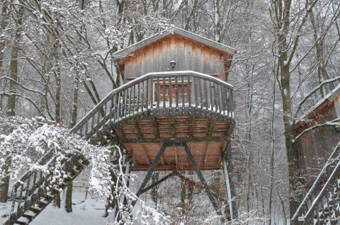 Casa del árbol de Baumhaushotel Solling, alojamiento glamping en bosque nevado de Baja Sajonia, invierno.