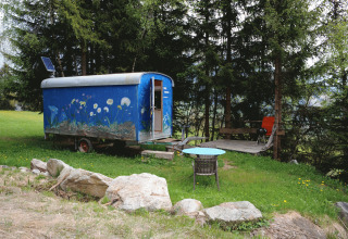 Glampingaccommodatie Zigeunerwagen in de Zwitserse Alpen met bloemenkunst, terras en bosrijke omgeving.