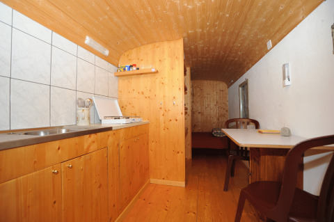 Binnenzicht van Glamping Sundelas - Zigeunerwagen Zwitserse Alpen met houten inrichting en keukentje.