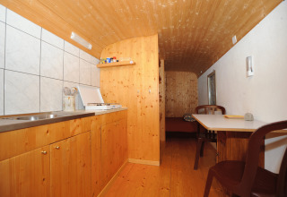 Interior view of Glamping Sundelas - Zigeunerwagen in the Swiss Alps, featuring wood decor and compact kitchen.