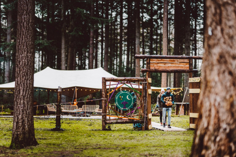 Stel bij de ingang van glamping Winterwoods - Yurts Drenthe, met tenten en lichtjes in het bos.