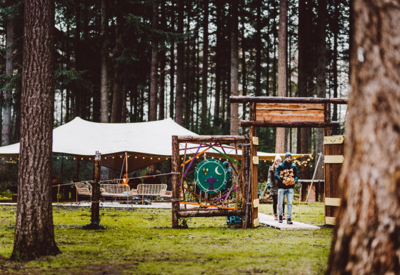 Stel bij de ingang van glamping Winterwoods - Yurts Drenthe, met tenten en lichtjes in het bos.