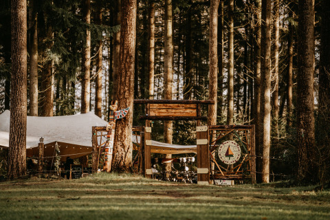 Glamping accommodatie bij Winterwoods - Yurts Drenthe, tussen de bomen met tent en houten ingangspoort.