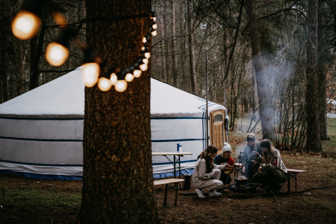 Glamping bij Winterwoods - Yurts Drenthe: groep mensen bij kampvuur voor een joert in het bos.