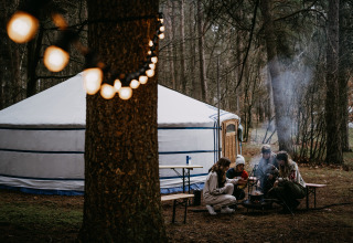 Glamping bij Winterwoods - Yurts Drenthe: groep mensen bij kampvuur voor een joert in het bos.