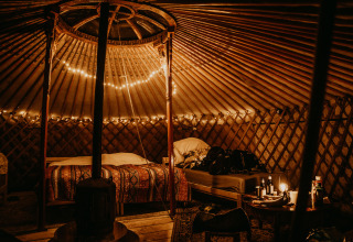 Sfeervol interieur van een glamping yurt bij Winterwoods, Drenthe met warme lichtjes en comfortabele bedden.