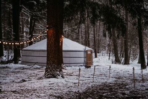 Glamping-accommodatie yurttent bij Winterwoods - Yurts Drenthe in een besneeuwd bos met sfeerverlichting.
