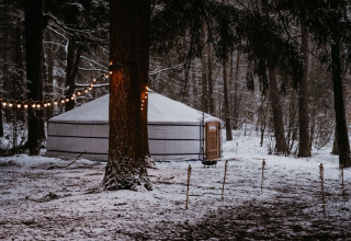 Glamping-accommodatie yurttent bij Winterwoods - Yurts Drenthe in een besneeuwd bos met sfeerverlichting.