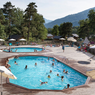 Outdoor swimming pools with guests relaxing by the deck at Huttopia Bourg-Saint-Maurice - Glamping Savoie.