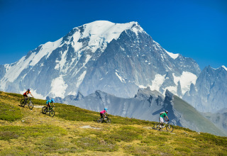 Ciclisti in mountain bike su un sentiero con le Alpi innevate sullo sfondo vicino a Huttopia Bourg-Saint-Maurice.