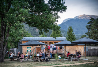 Udendørs spiseområde med familier og venner ved Huttopia Bourg-Saint-Maurice glamping, omgivet af bjerge.