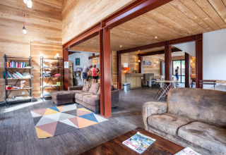 Sala comune moderna con interni in legno e divani a Huttopia Bourg-Saint-Maurice - Glamping Savoie.