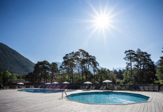 Piscine extérieure chez Huttopia Bourg-Saint-Maurice - Glamping Savoie, entourée de montagnes et de pins sous le soleil.