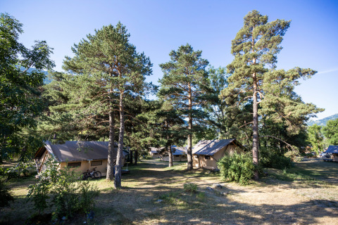 Glamping-Unterkünfte bei Huttopia Bourg-Saint-Maurice in Savoie, mit Zelten zwischen hohen Bäumen.