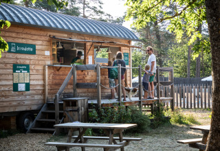 Famiglia con cane a una roulotte di legno presso Huttopia Bourg-Saint-Maurice Glamping Savoie, immersi nel verde.