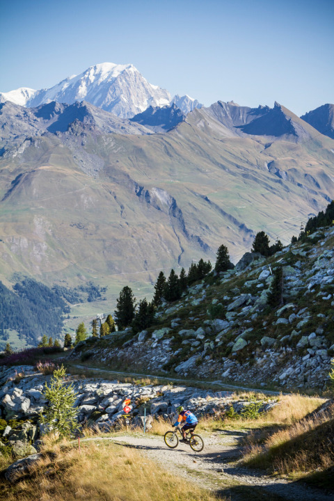 Mountainbikere cykler på en natursti med udsigt til sneklædte bjerge nær Huttopia Bourg-Saint-Maurice.