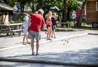 Famille jouant à la pétanque sur un terrain extérieur au Huttopia Bourg-Saint-Maurice - Glamping Savoie.