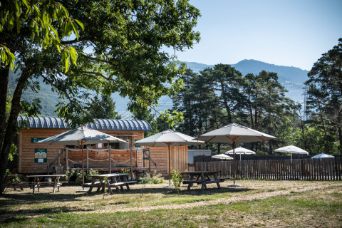 Alojamiento glamping con cabaña de madera y sombrillas en Huttopia Bourg-Saint-Maurice, Savoie.