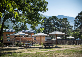 Hébergement glamping avec cabane en bois et parasols chez Huttopia Bourg-Saint-Maurice en Savoie.